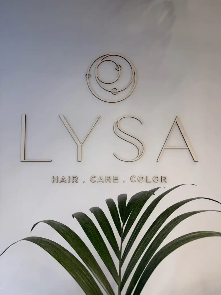 Het LYSA Hair Care Color logo aan de muur met houten letters