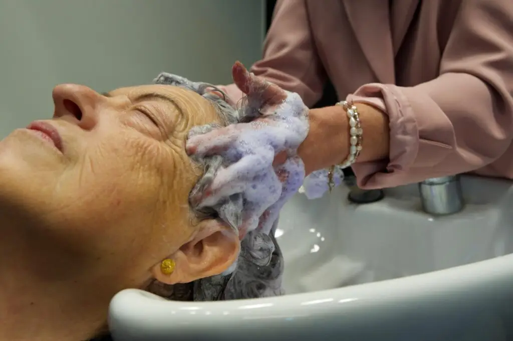 Dame die de haren wast van de klant in de shampoo bowls, LYSA Turnhout